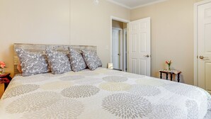 A bedroom with a large bed, a wooden headboard, and a nightstand with a vase of flowers. - 1 Mi to Boat Ramp: Peaceful Deal Island Home! (Deal Island Historic District)