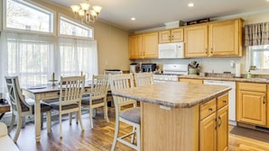A spacious kitchen with wooden cabinets, a granite countertop, and a dining area with chairs and a table. - 1 Mi to Boat Ramp: Peaceful Deal Island Home! (Deal Island Historic District)