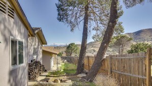 Un quartier résidentiel avec une maison, une clôture en bois, un arbre et un ciel dégagé.