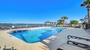 A swimming pool with lounge chairs and a view of the sea. - Waterfront Gem w/ Balcony in Garden City (Murrells Inlet)