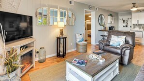 A living room with a TV, a fireplace, a coffee table, and a leather chair. - Waterfront Gem w/ Balcony in Garden City (Murrells Inlet)