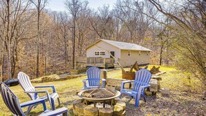 A cabin with a deck, surrounded by a fire pit and Adirondack chairs. - Peaceful Cabin at Lake Logan w/ Spacious Yard! (Ardmore)