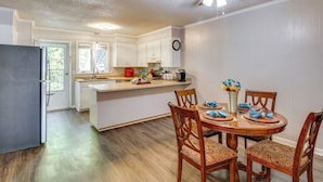 Una cocina moderna con armarios blancos, una mesa de comedor de madera con servilletas azules, y un ventilador de techo.