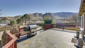 Un patio con una parrilla, suelo de losas de piedra y vistas a colinas distantes.
