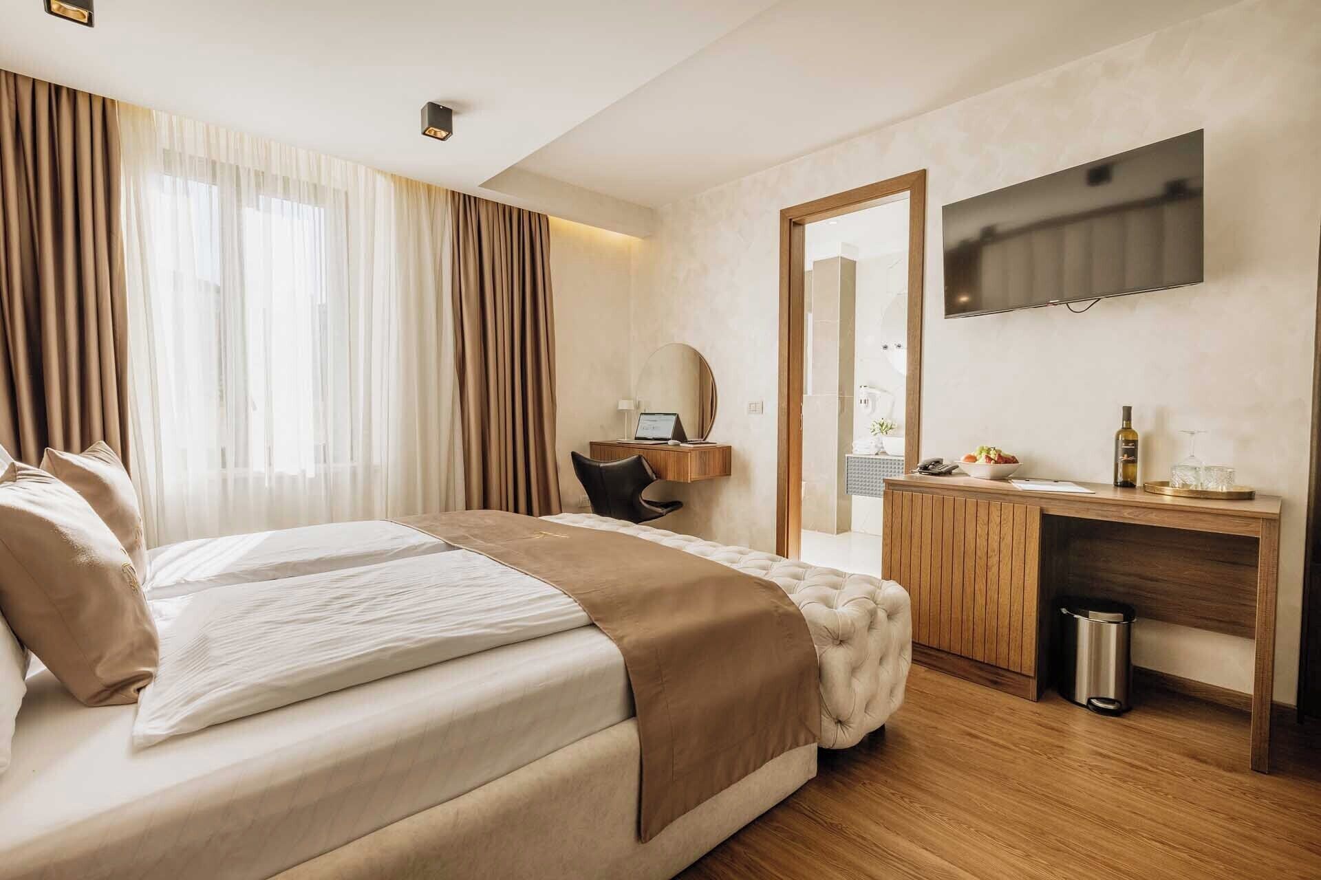 Une chambre d’hôtel avec un grand lit, un bureau avec un ordinateur, une télévision et un minibar.