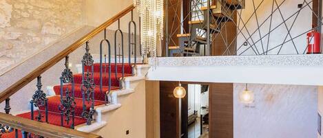 A grand staircase with ornate black railings and red carpeted steps leading to a second floor.