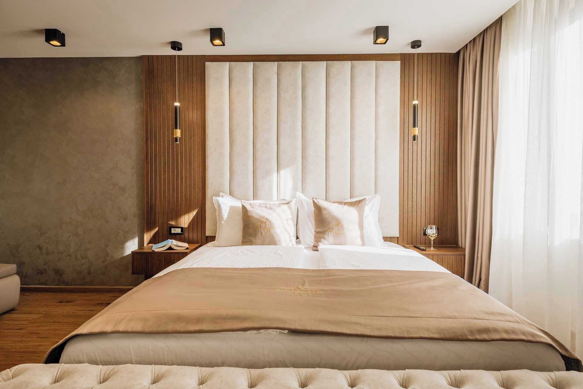 A modern hotel room with a large bed, wooden paneling on the walls, and a view of the city.
