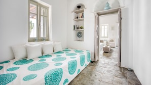 Ein Schlafzimmer mit Bett, Fenster, Tür und einem Flur, der in einen anderen Raum führt.