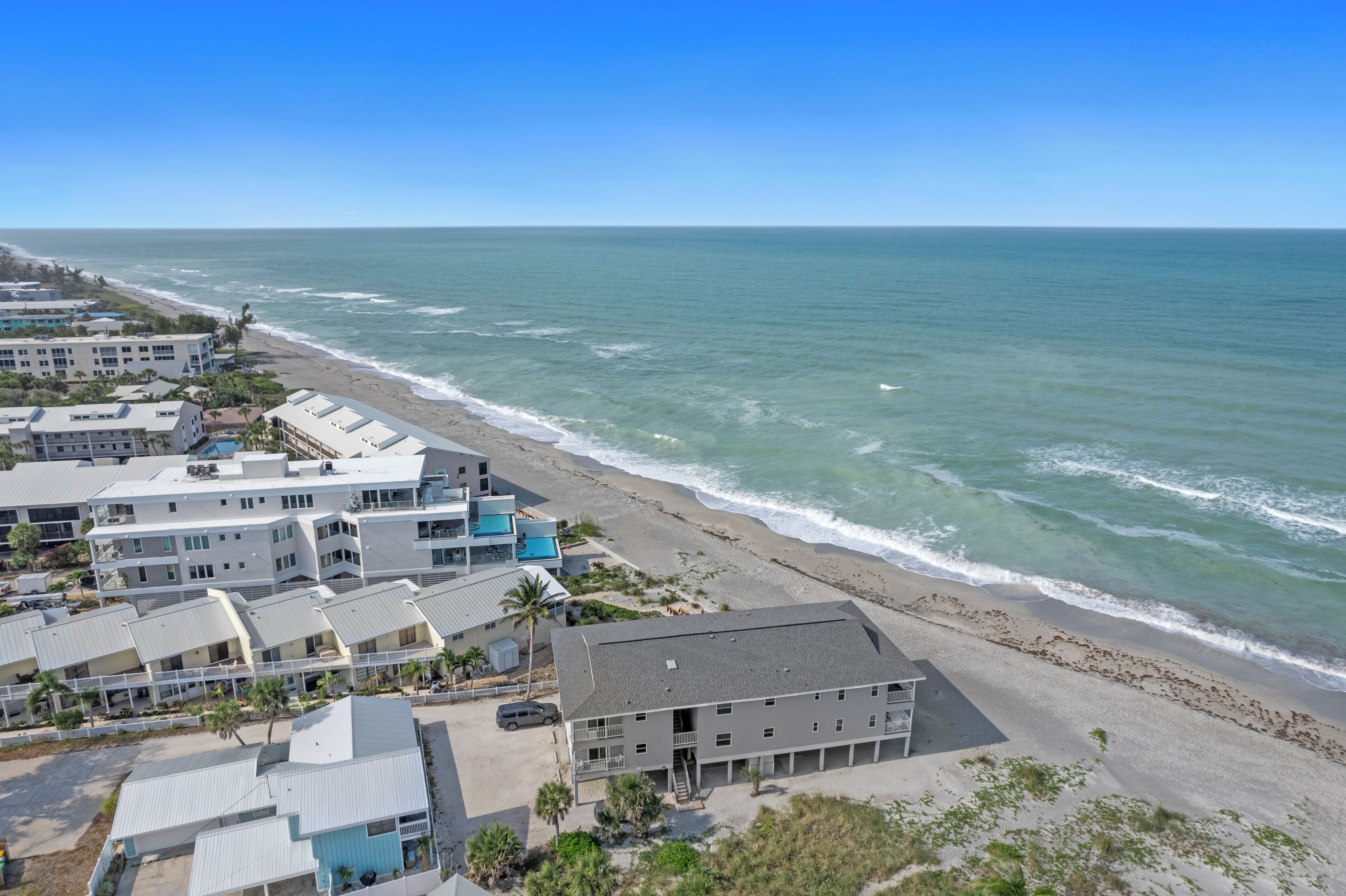 Un hotel frente al mar con varias construcciones, una playa y el océano.