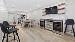 A modern kitchen with a dining area, built-in wine rack, and a large TV.