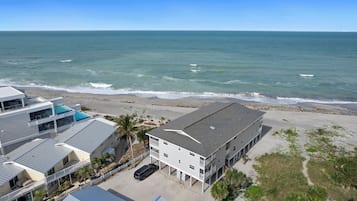 A beachfront hotel with multiple buildings, a swimming pool, and a view of the ocean.