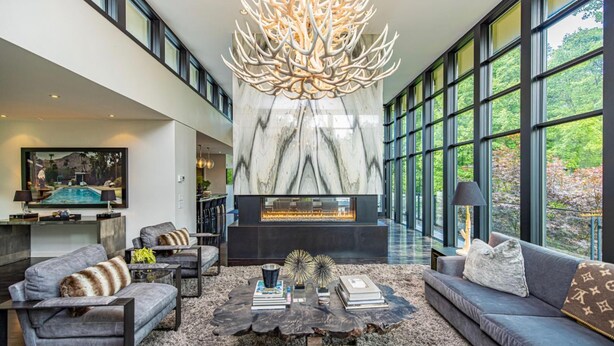 A spacious living room with a fireplace, large windows, and modern furniture. - Stunning 6 bed 5 bath estate on 65 acres with Pool, Hot Tub and Tennis Court! (Caledon Village)