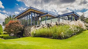 A modern house with large glass windows, a stone facade, and a well-maintained garden. - Stunning 6 bed 5 bath estate on 65 acres with Pool, Hot Tub and Tennis Court! (Caledon Village)