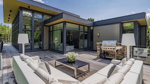 A modern house with a large deck, outdoor seating, and a barbecue area. - Stunning 6 bed 5 bath estate on 65 acres with Pool, Hot Tub and Tennis Court! (Caledon Village)
