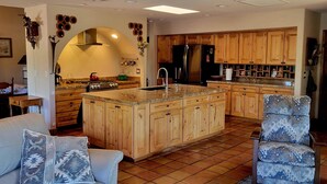 A spacious kitchen with wooden cabinets, a central island, and a dining area with a sofa and chair. - The Camelback Ranch in Litchfield Park - Amazing Backyard | Refreshing Pool (Litchfield Park)