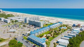 Ein Küstenhotel mit mehreren Gebäuden, einem Parkplatz und einem Strand im Hintergrund.
