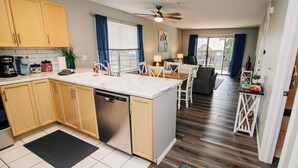 A modern kitchen with wooden cabinets, a dishwasher, and a dining area with a table and chairs.