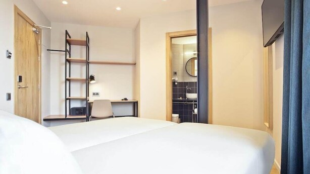 A modern hotel room with a large bed, a desk, and a built-in wardrobe. - Hotel Climent (Barcelona)