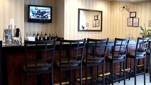 Un área de bar con sillas de madera y un televisor en la pared.