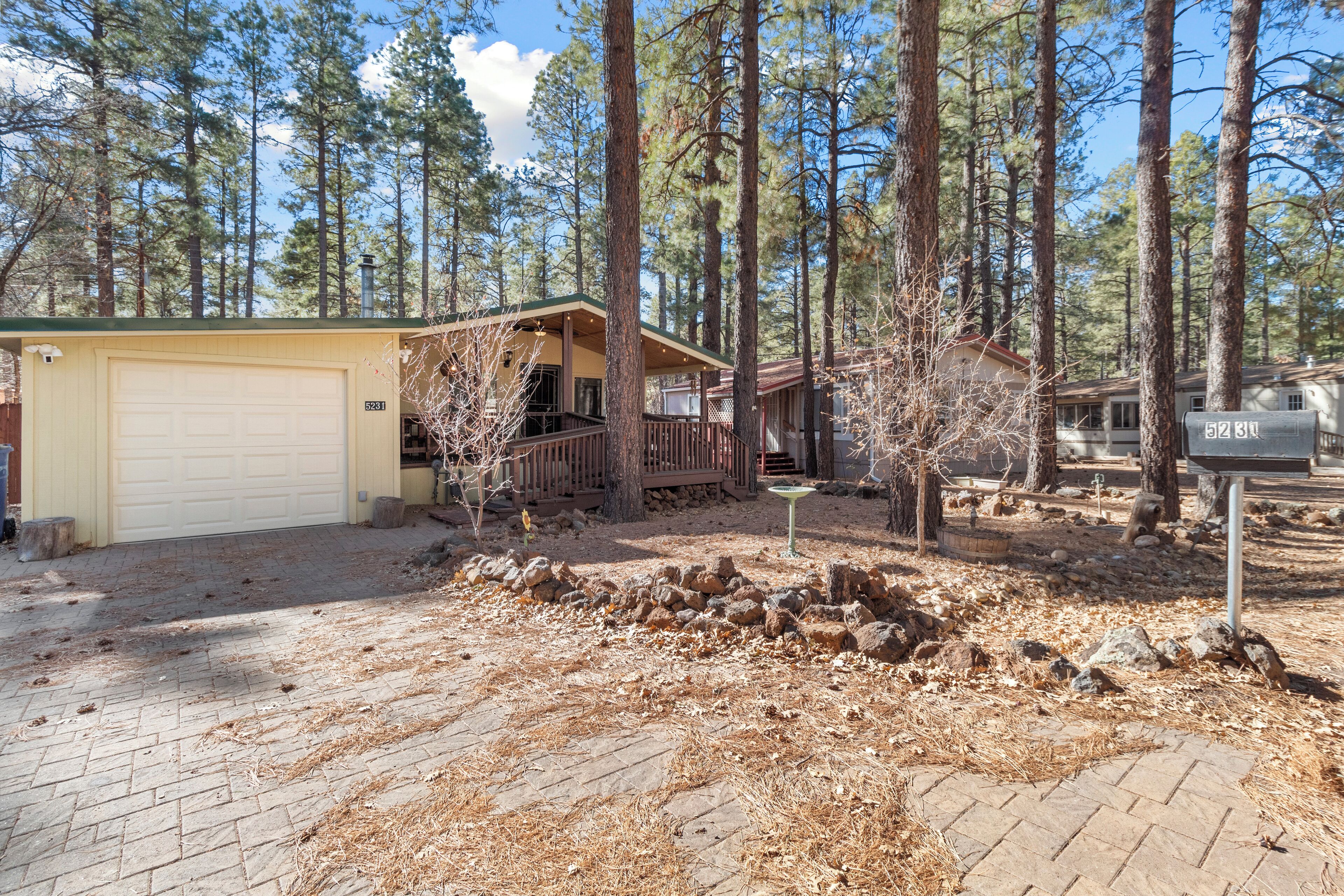 A cabin with a garage, surrounded by a forest.