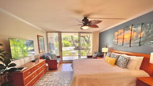 A bedroom with a bed, a ceiling fan, a TV, and a view of the outdoors. - Gorgeous Napili Shores studio A/C (Lahaina)