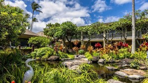 A hotel courtyard with a pond, lush greenery, and a building with balconies. - Gorgeous Napili Shores studio A/C (Lahaina)