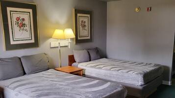 A hotel room with two beds, a nightstand, a lamp, and framed floral artwork on the walls.
