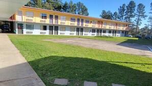 Un motel de dos pisos, con estacionamiento y zona verde.