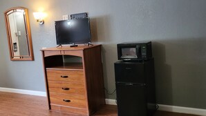 Una habitación con un escritorio de madera, televisor y microondas.