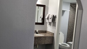Un baño con lavamanos de encimera de granito, un espejo y un inodoro.