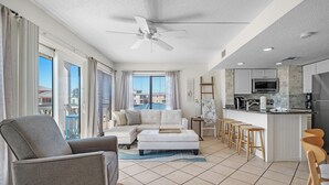 Una sala moderna con un sofá, un reposapiés y un comedor con taburetes.