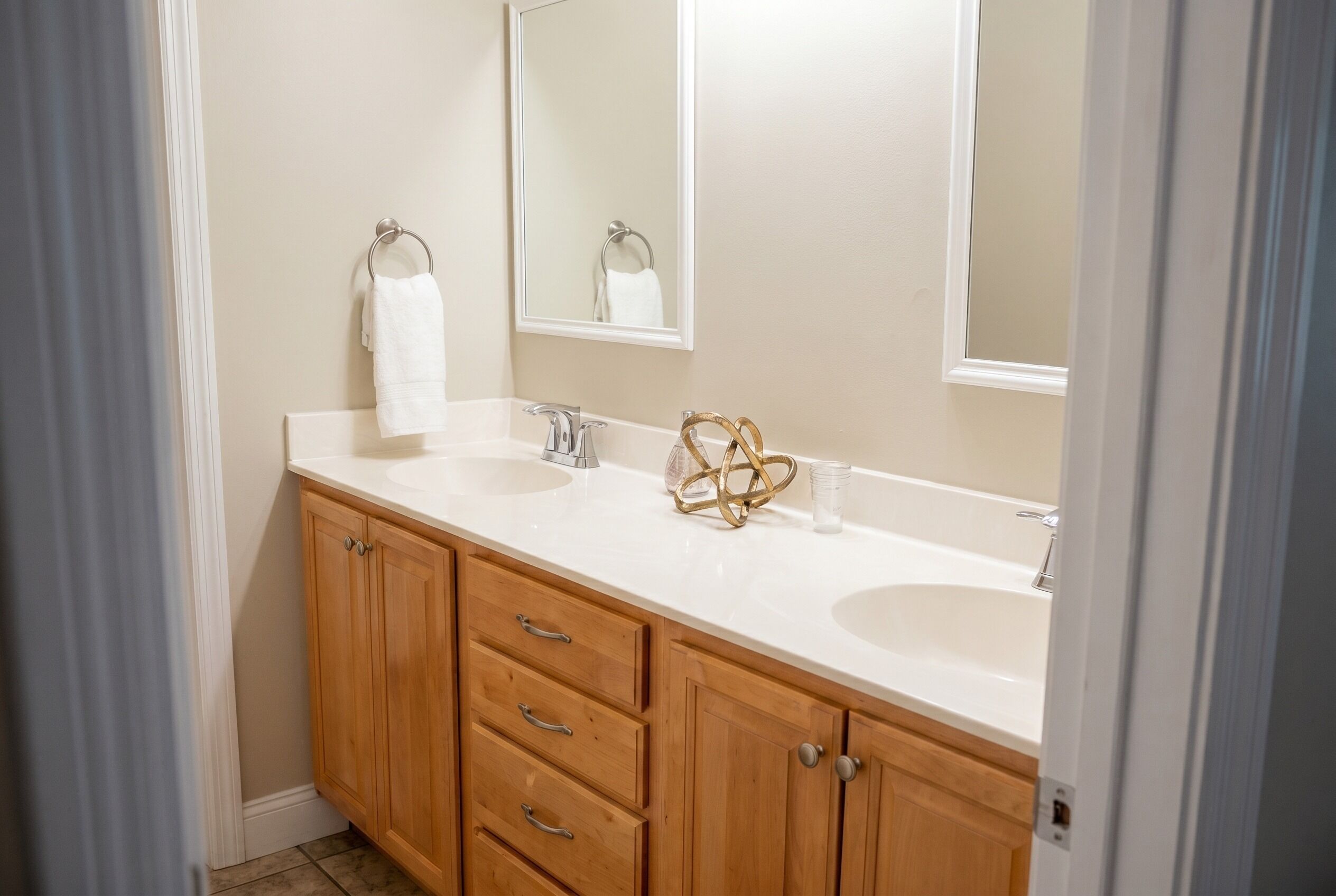 Une salle de bain avec deux lavabos, des meubles en bois, un miroir et un porte-serviettes.