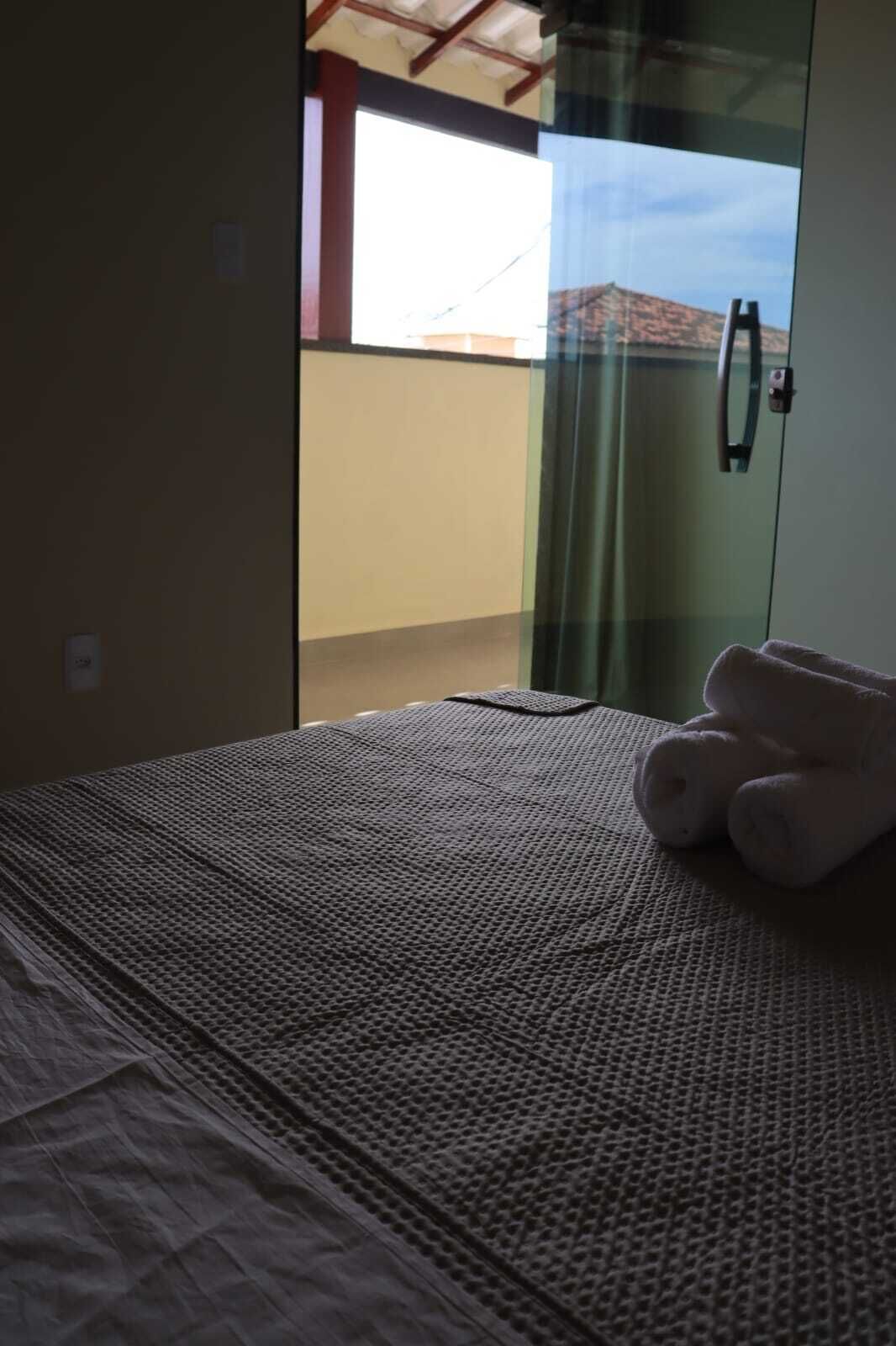 A room with a bed, a glass door leading outside, and a teddy bear on the bed.