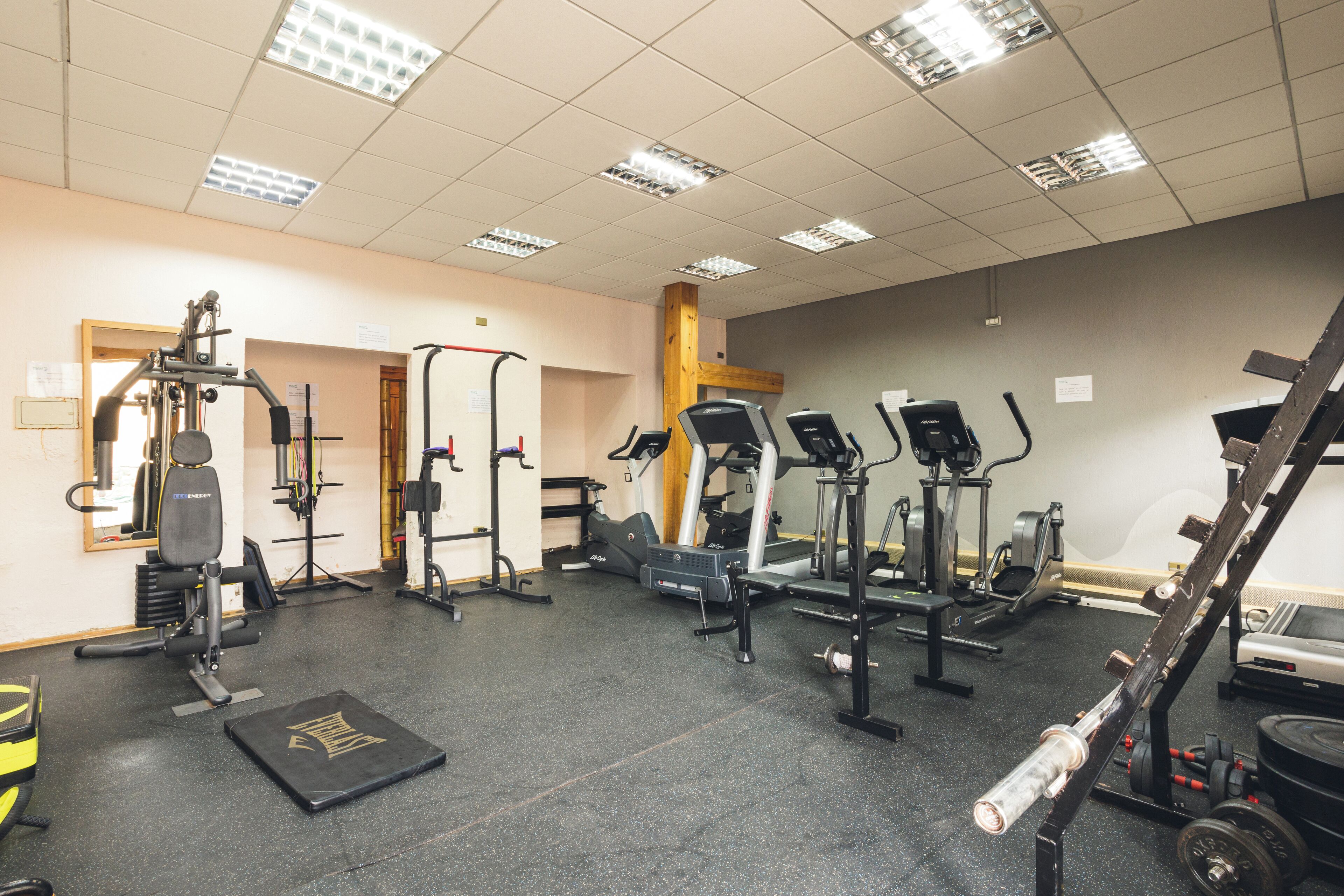 A gym with various exercise equipment, including treadmills, weight machines, and free weights.