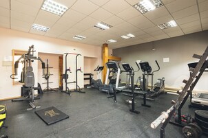 Un gimnasio con varios equipos de ejercicio, incluyendo cintas de correr, máquinas de pesas y pesas libres.