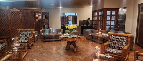 A spacious lobby with a variety of seating options, including patterned chairs and sofas, arranged around a central wooden coffee table.