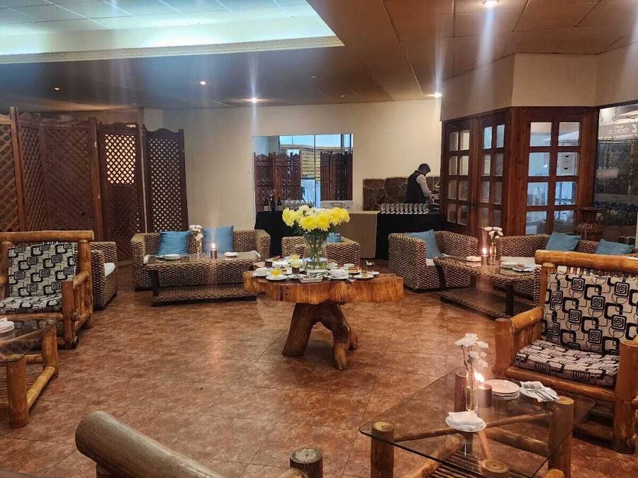 A spacious lobby with a variety of seating options, including patterned chairs and sofas, arranged around a central wooden coffee table.