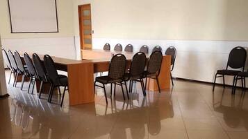 Un salón de conferencias con una larga mesa, sillas, una pantalla de proyector y una puerta.