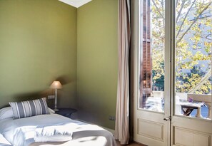 A room with a bed, a nightstand, a lamp, and a window with curtains. - Barna House B&B (Barcelona)