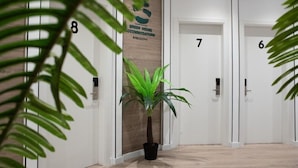 Ein Flur mit Türen mit den Nummern 6 bis 8, einer Zimmerpflanze und einem Schild für Green House Accommodations in Barcelona.
