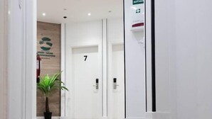 Ein moderner Hotelkorridor mit Holzboden, einer Zimmerpflanze und einer Tür mit der Nummer 7.