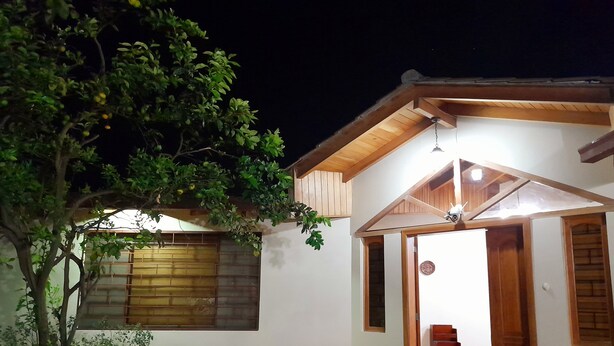 Una casa moderna con fachada de madera, una escalera visible y un ventanal con persianas.