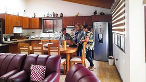 Una cocina moderna con armarios de madera, un comedor con sillas de cuero rojo y un refrigerador con imanes.