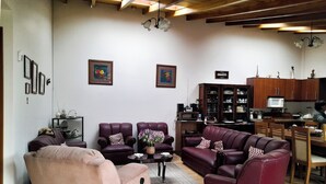 Una sala de estar con dos sofás, una mesa de centro y un comedor con cocina al fondo.
