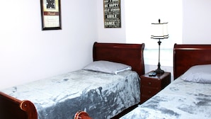 A bedroom with two beds, a bedside table with a lamp, and a wall with motivational quotes.