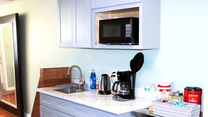 A kitchen with a built-in microwave, a coffee maker, and a sink.