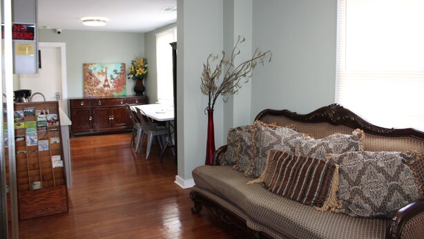 A living room with a sofa, a dining table, and a kitchen area.