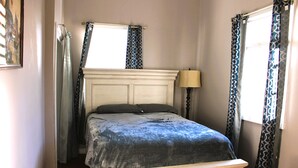 A bedroom with a bed, a nightstand, a lamp, and a chair. - 1 Bedroom Suite upstairs (NEW ORLEANS)