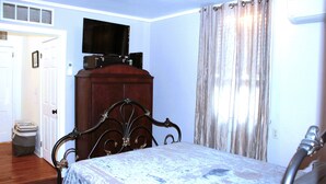 A bedroom with a bed, a wooden dresser, a television on top of the dresser, and a window with curtains. - 2 Bedroom Suite on second floor (NEW ORLEANS)