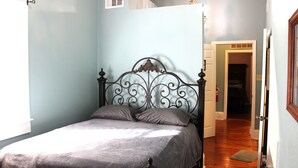 A bedroom with a metal bed frame, a grey bedspread, and a wooden floor.